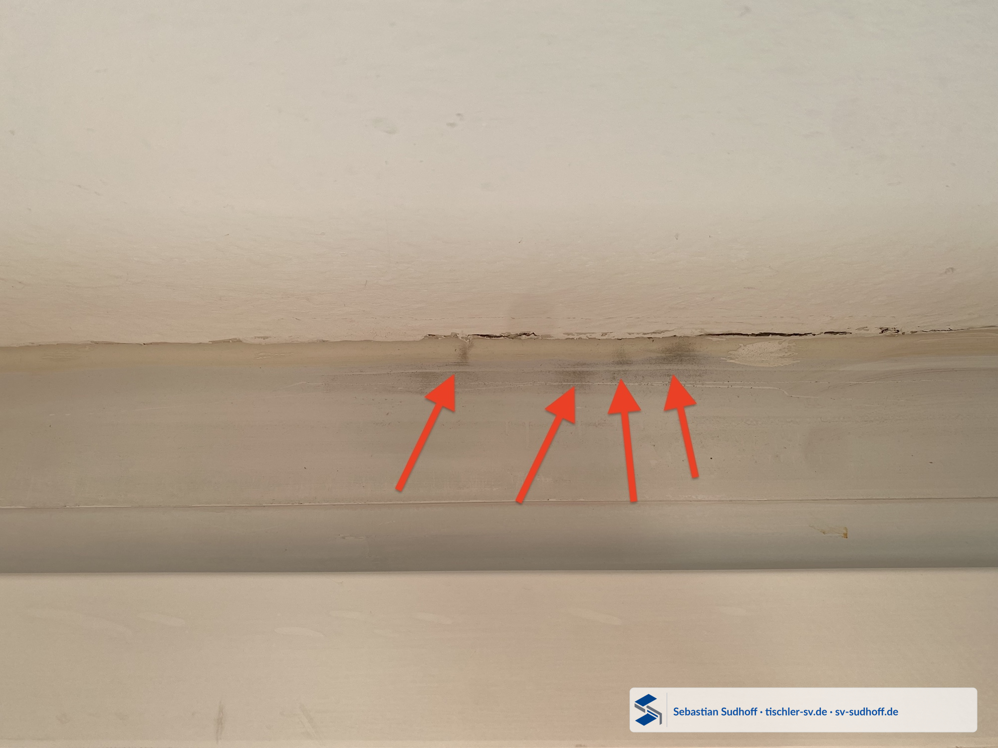 Graue streifenförmige Ablagerungen am oberen Fensterrahmen unter einer gerissenen Anschlussfuge zur Decke