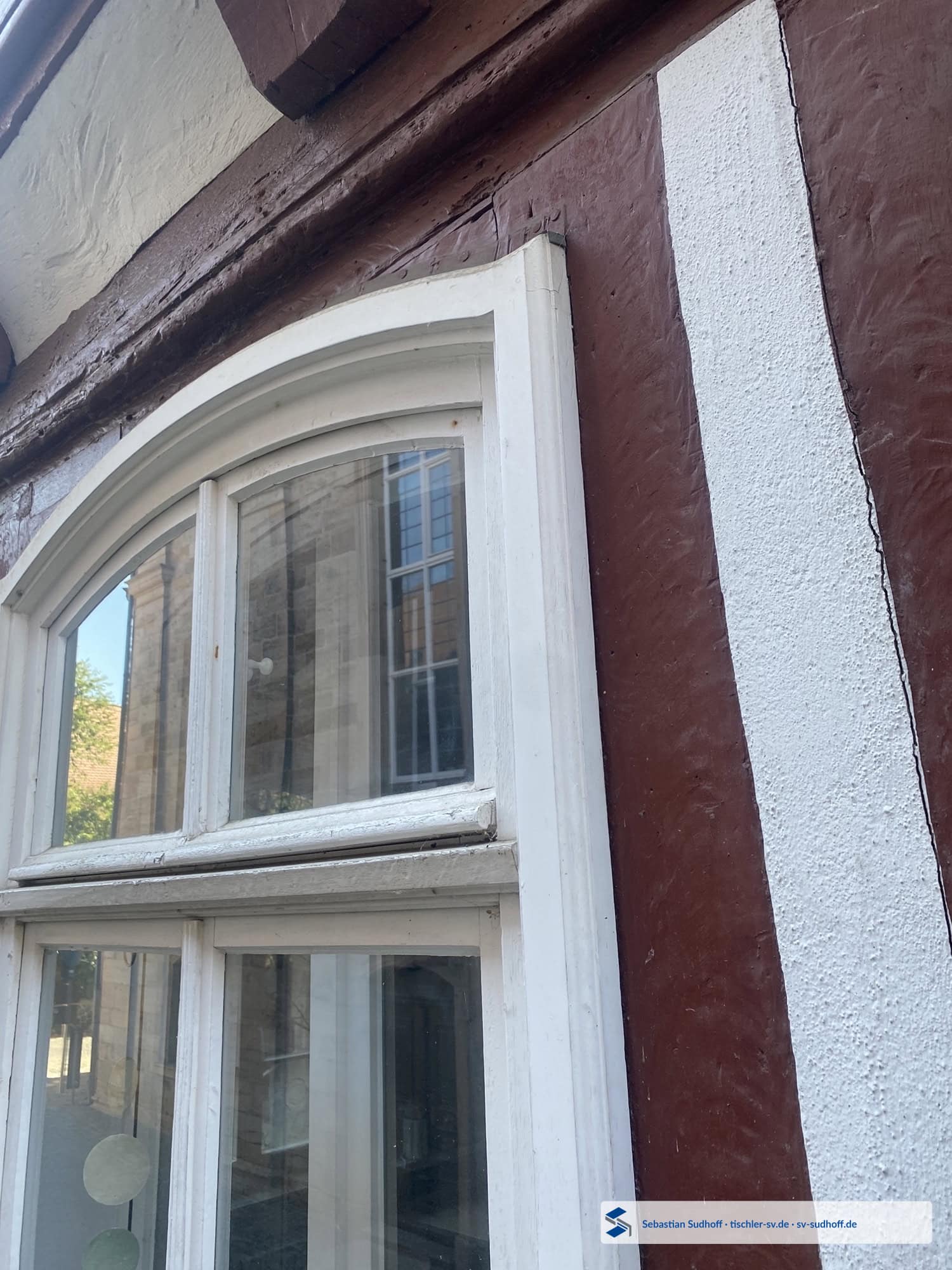 Handwerklich abgedecktes Rahmenprofil am oberen Holzfensteranschluss unter einem Dachüberstand