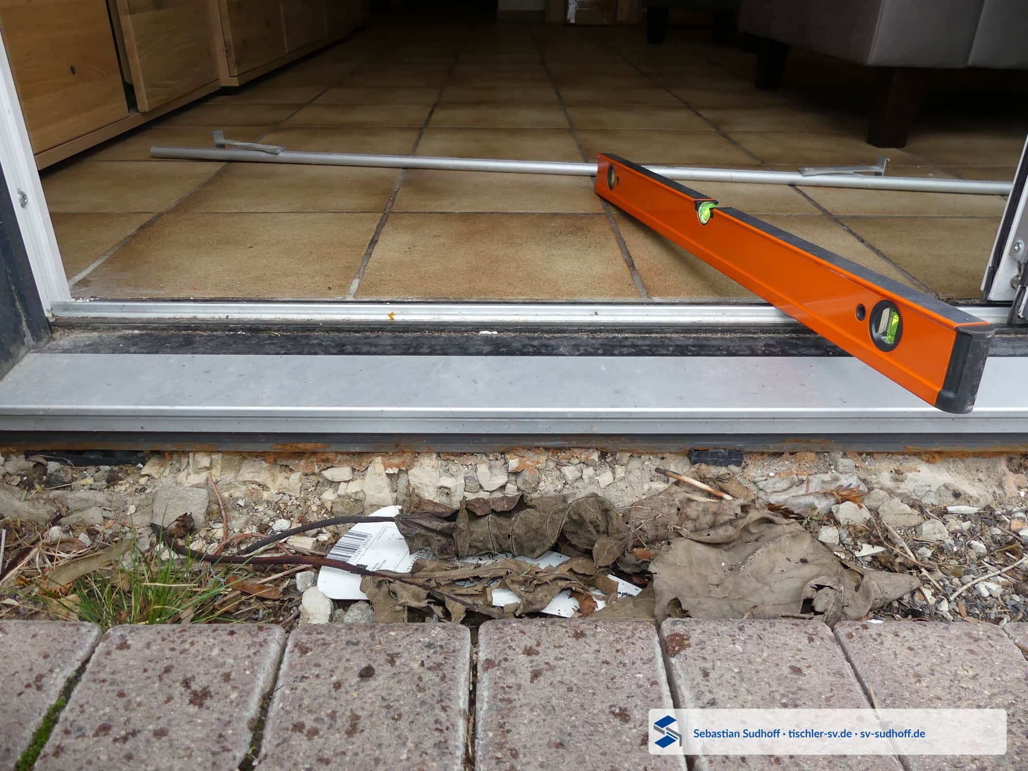 Poröser bröseliger Untergrund mit Staub und Schutt unter einer Hebeschiebetür