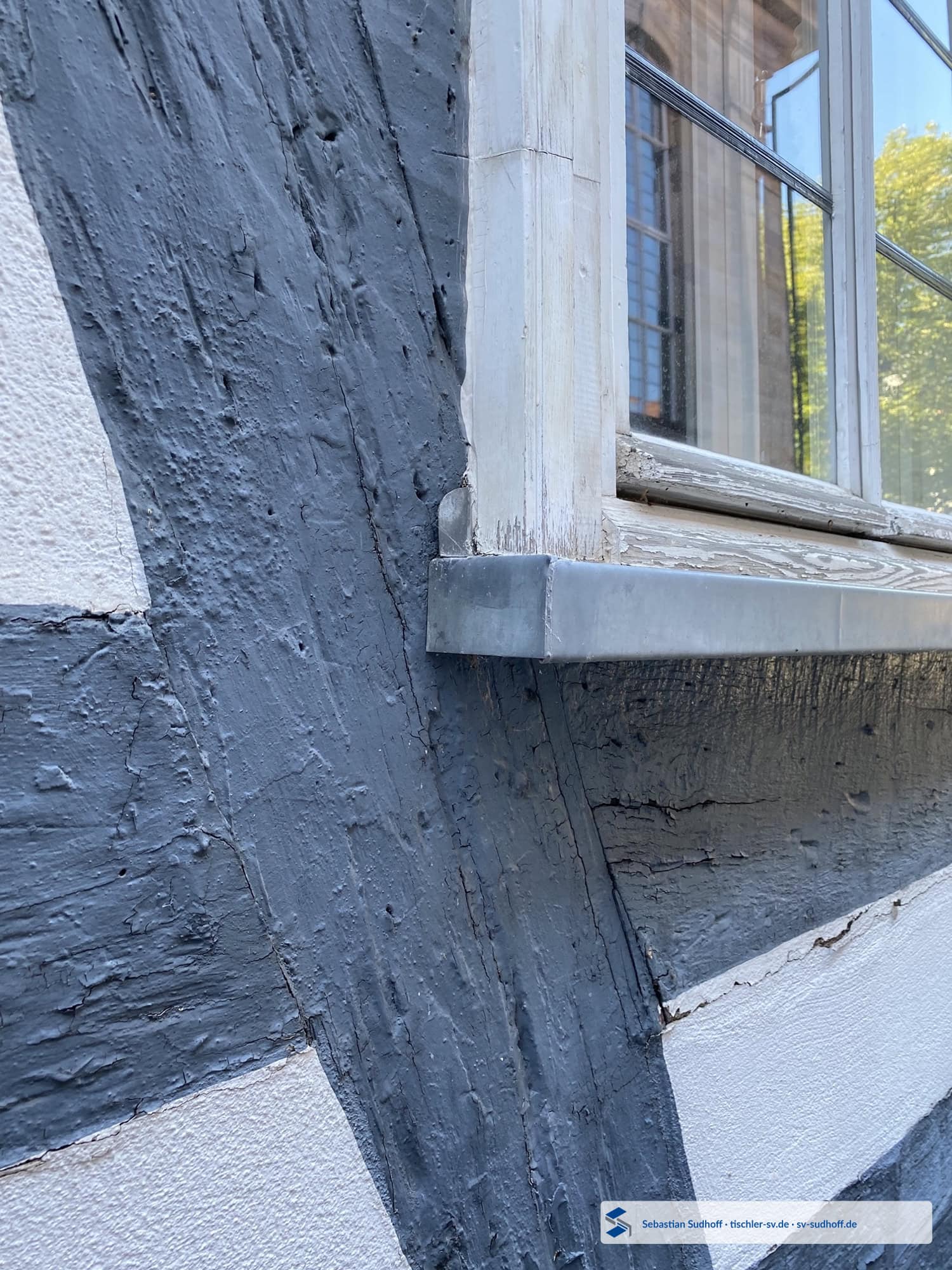Erneuerter Holzbereich am unteren Fensteranschluss über einer Zinkfensterbank