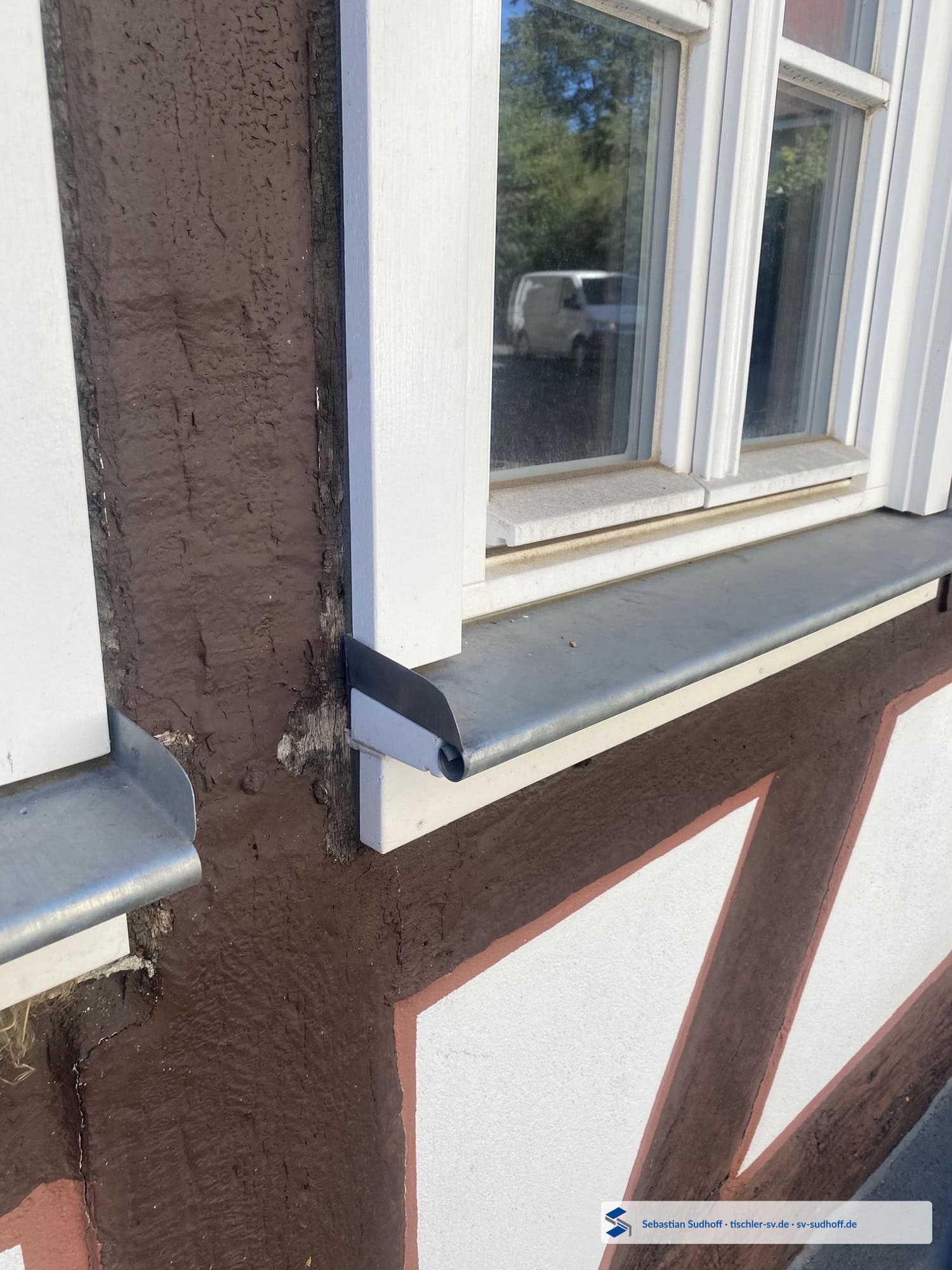 Fensterbank mit Gefälle und freier Wasserableitung unter einem Holzfenster