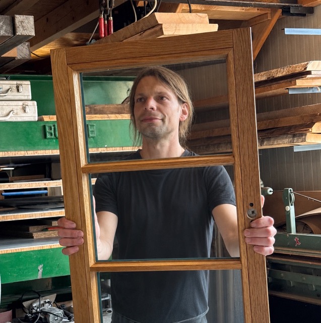 Sebastian Sudhoff mit einem Holzfenster in der eigenen Tischlerei