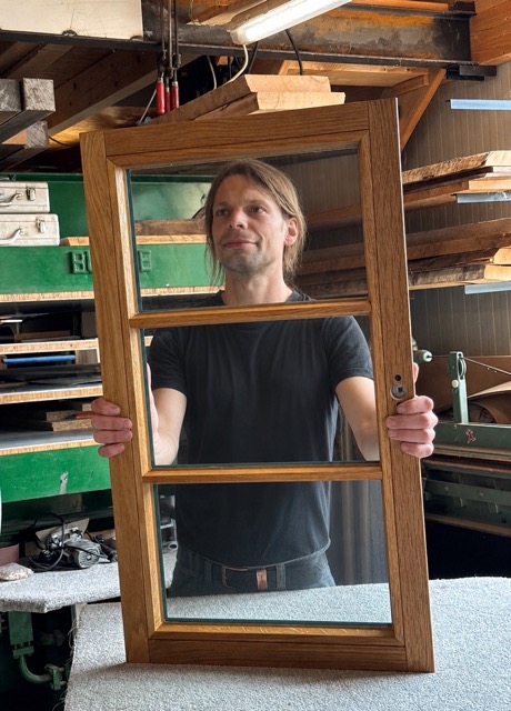 Sebastian Sudhoff mit einem Holzfenster in der eigenen Tischlerei